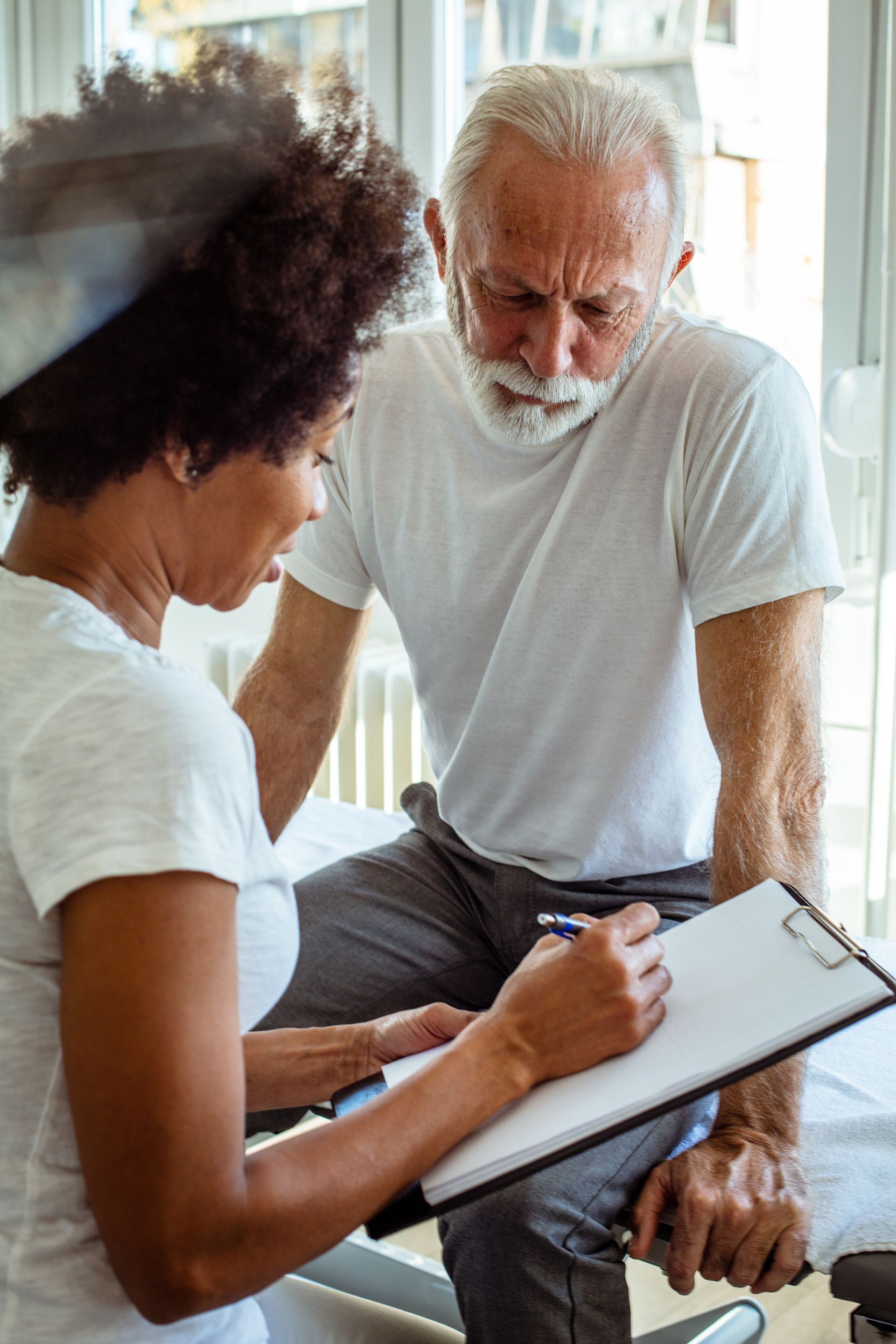 best chiropractor consultation with senior patient reviewing treatment plan on clipboard indoors. best chiropractor consultation with senior patient reviewing treatment plan on clipboard indoors.