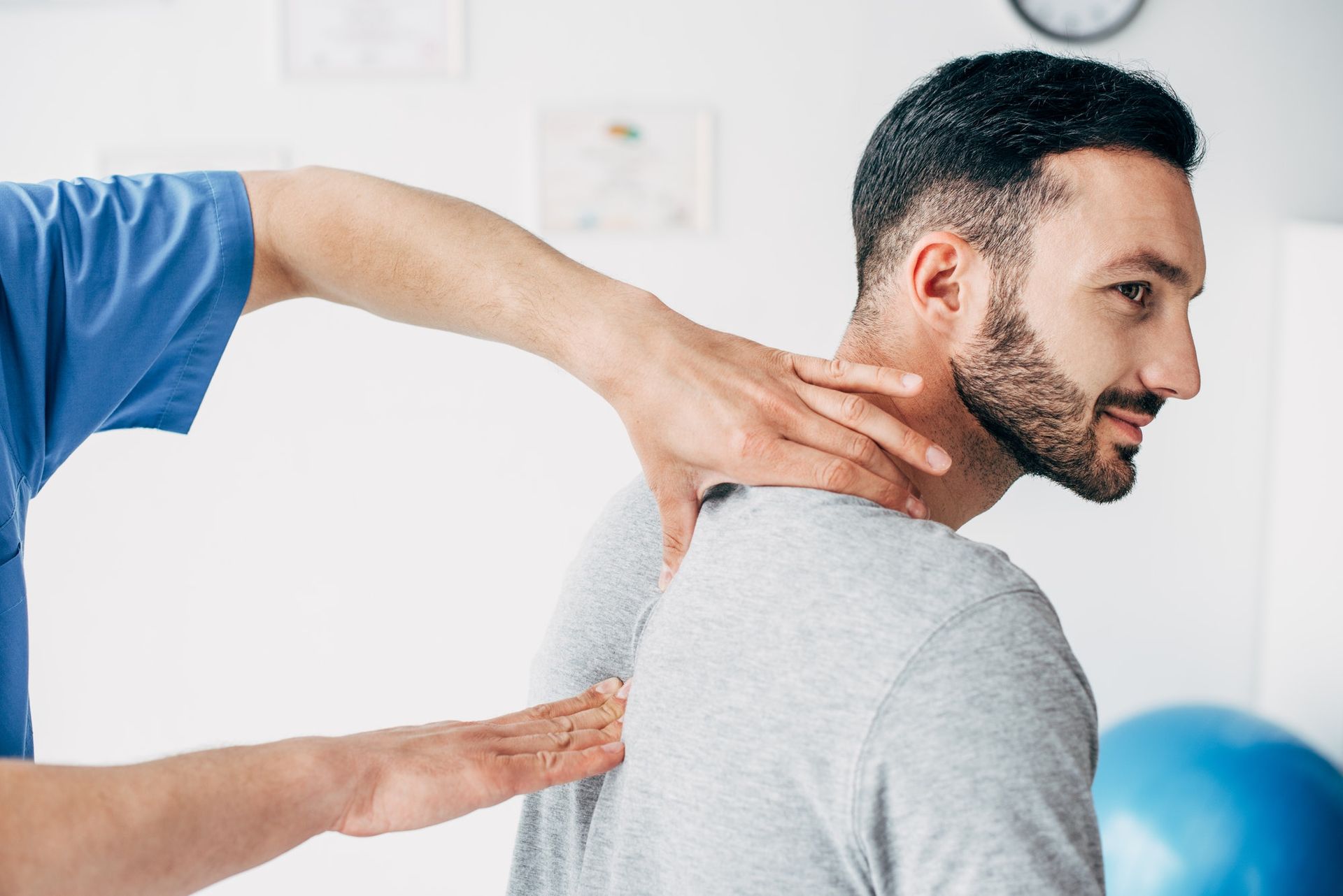 Physiotherapist examining a patient's neck and back, smiling, in a bright clinic.