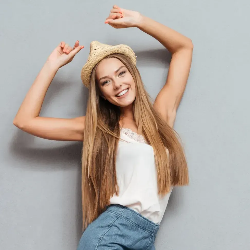 Woman with white tank top, straw hat, and blue jean skirt dancing