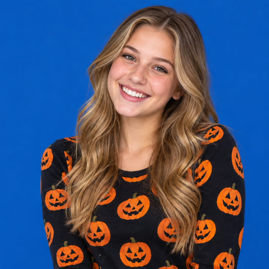 Smiling person in a black shirt with orange jack-o’-lanterns on a blue background