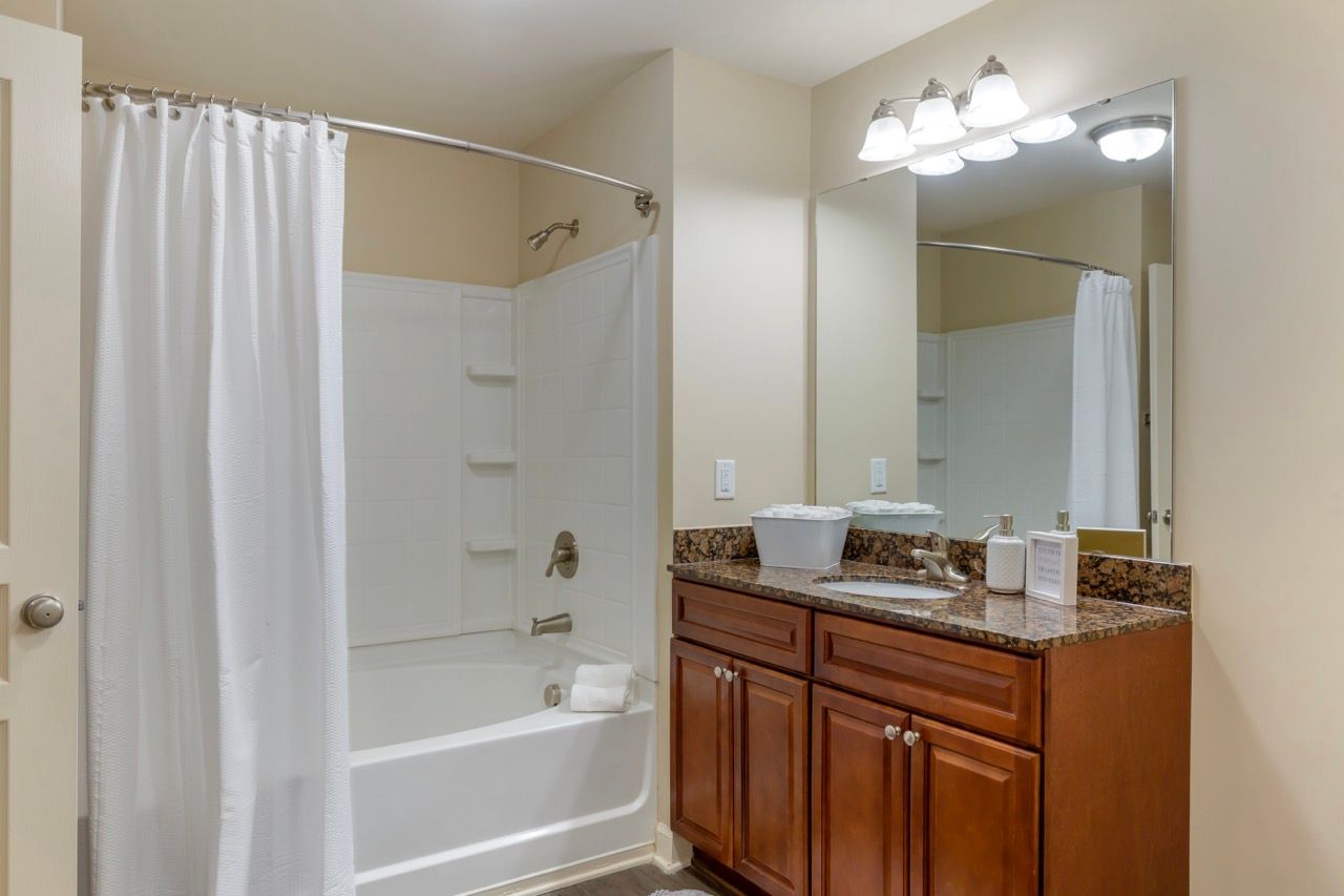 Bathroom with tub/shower, white tile surround, and a dark granite vanity.