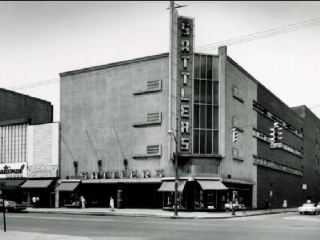 Black and white photo of the Sattlers department store building on a street corner, featuring a large vertical sign.