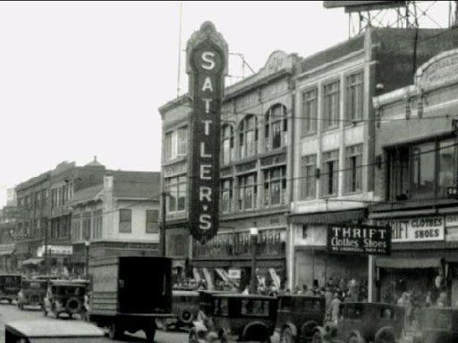 Black-and-white street view of a city block featuring a large vertical