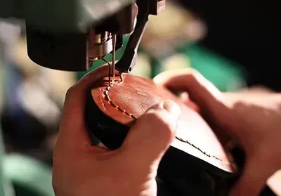 A person is sewing a shoe with a machine.