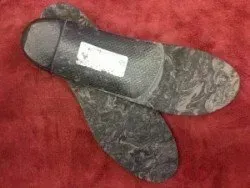 A pair of black insoles sitting on top of a red carpet.