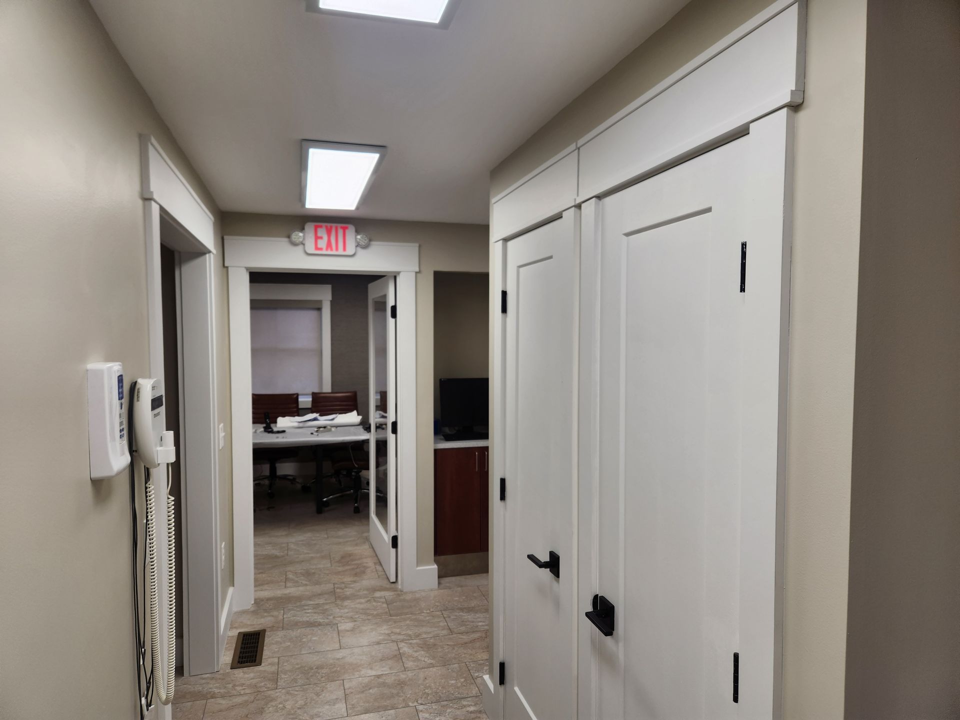 A hallway with a red exit sign on the wall