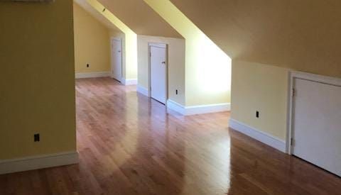 An empty attic with hardwood floors and yellow walls.