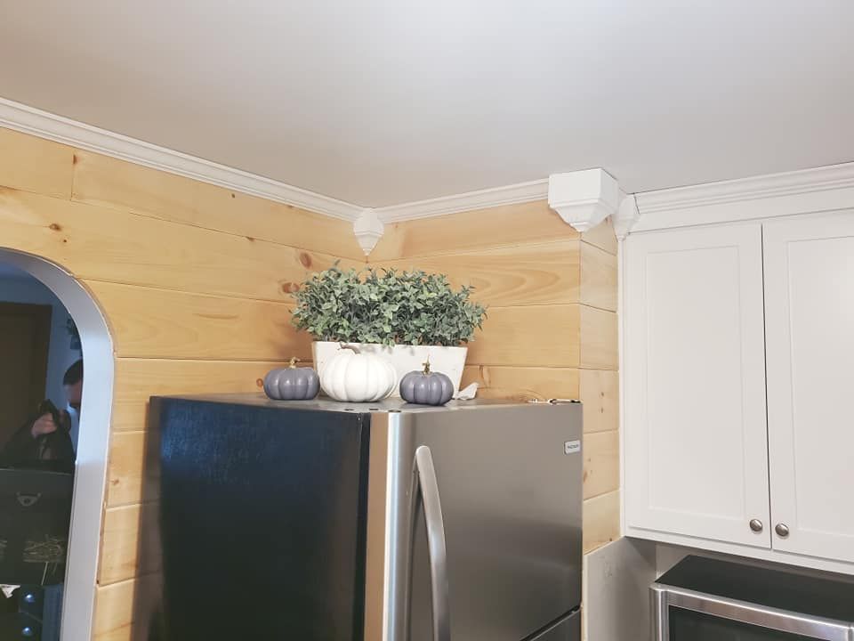A kitchen with a black refrigerator and white cabinets.