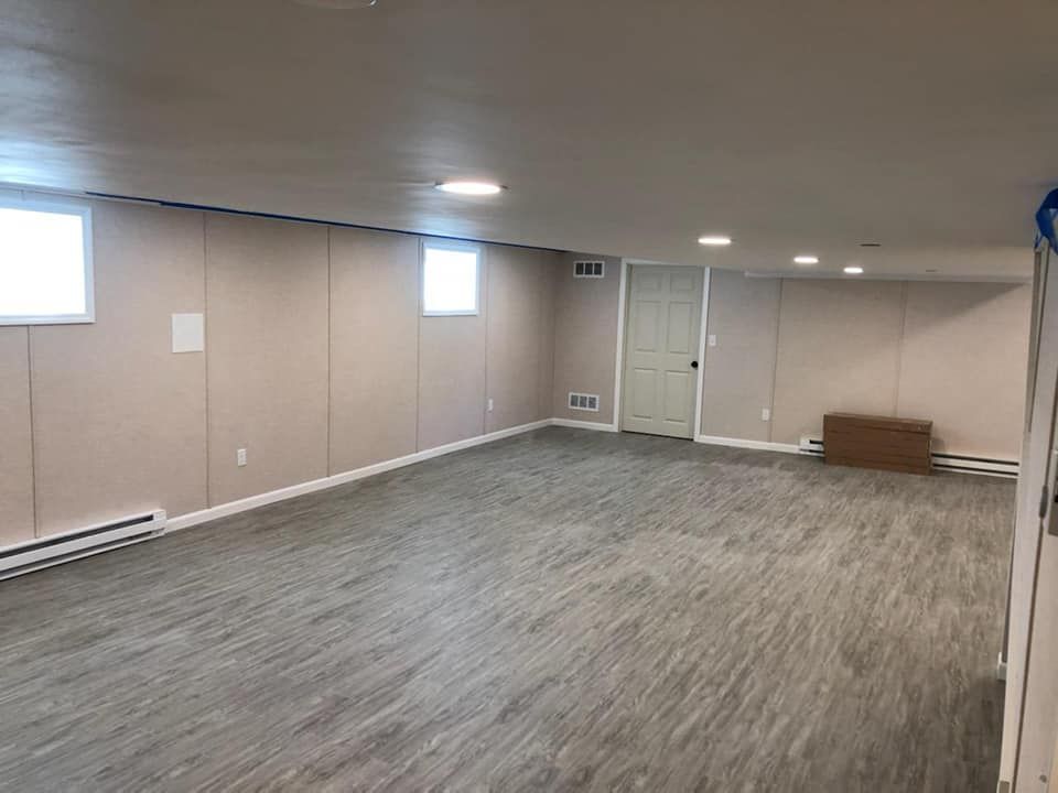 An empty basement with a wooden floor and a door.