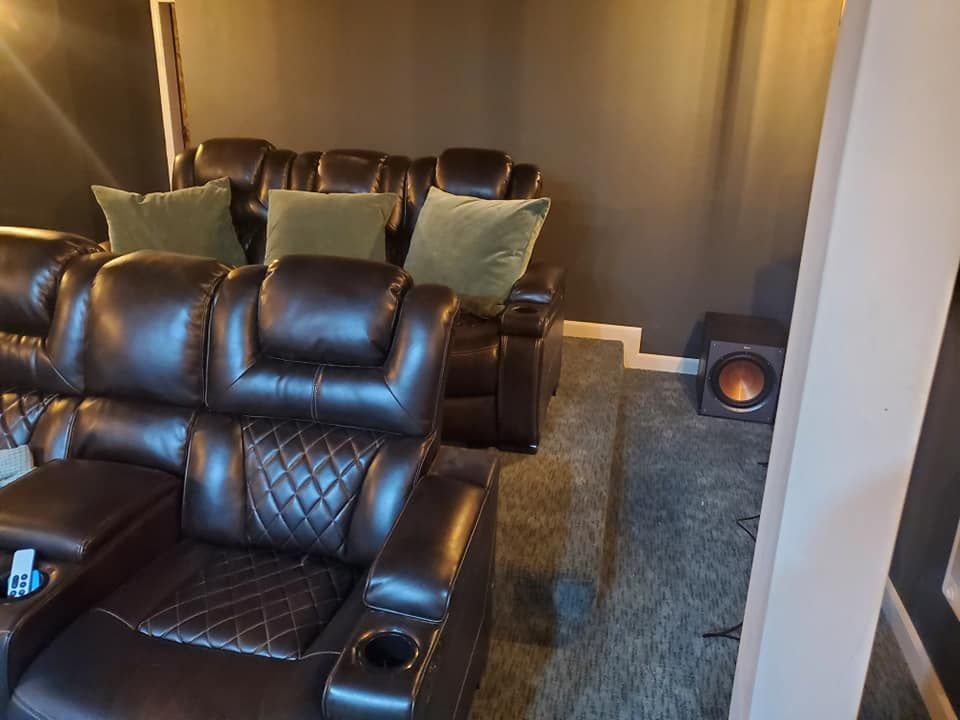 A home theater with a couch and chairs and a subwoofer.