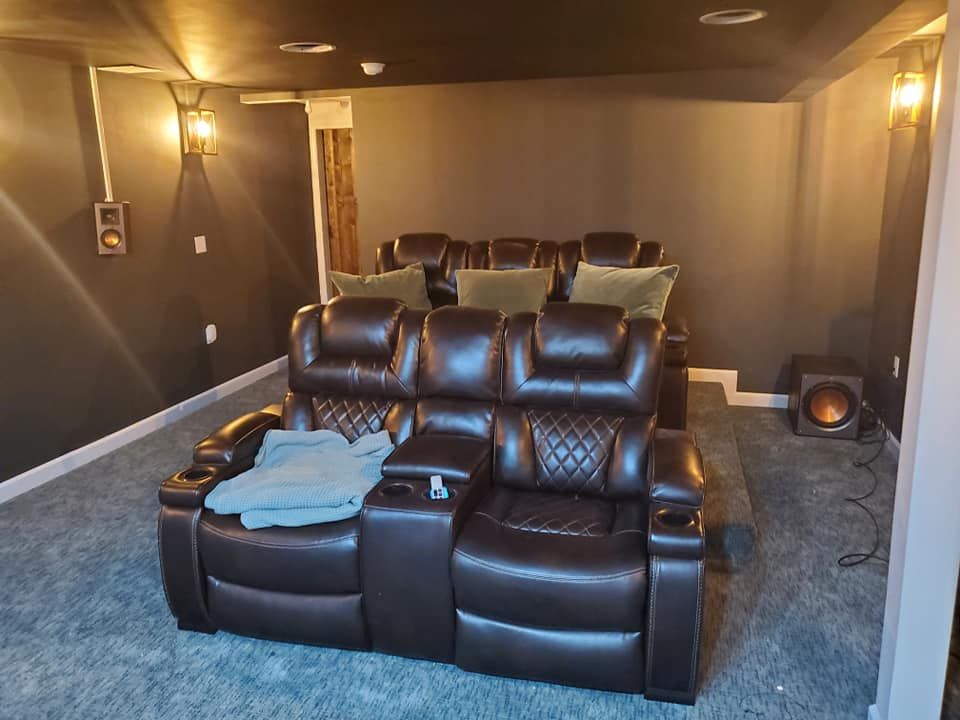 A home theater with a couch and chairs in it.