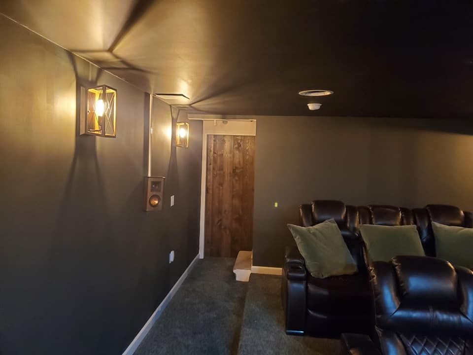 A home theater with black chairs and a black ceiling.
