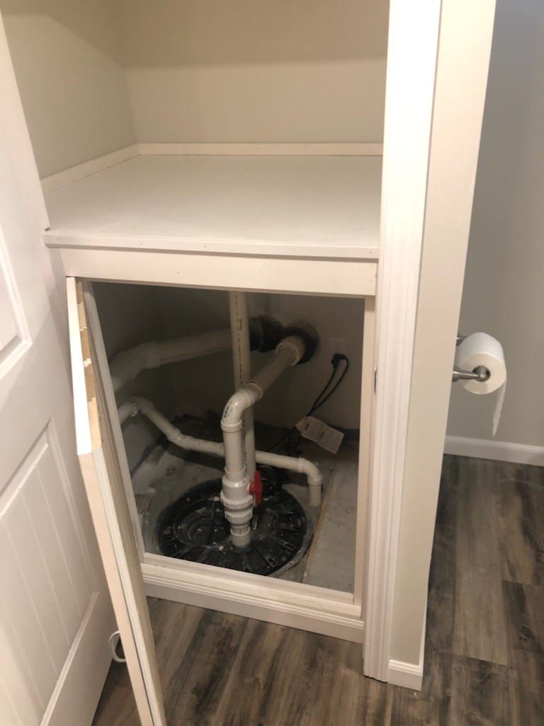 A basement drain pump is sitting inside of a closet.