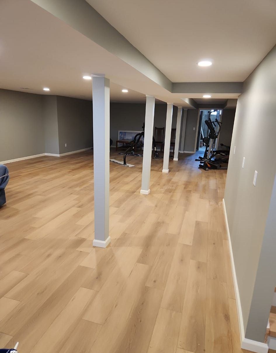 A large room with hardwood floors and columns.