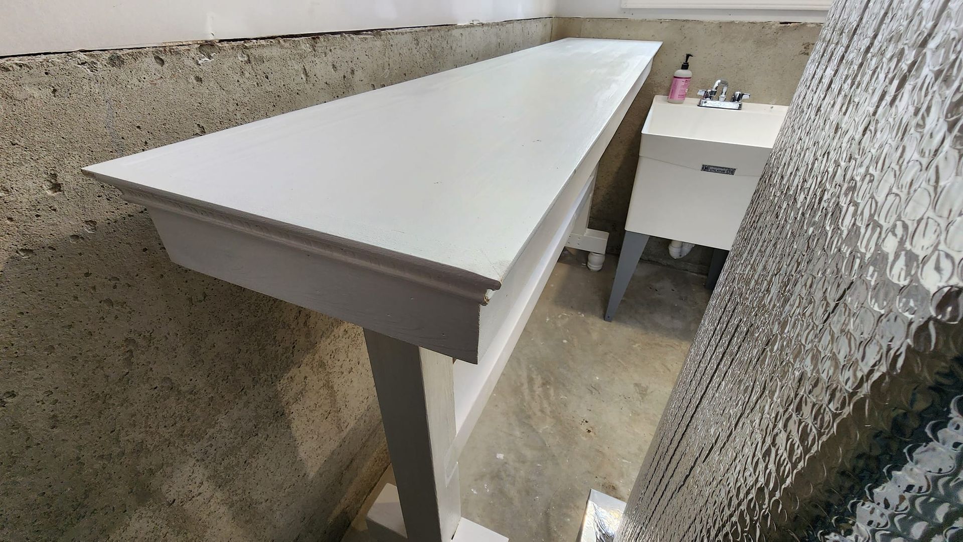 A white table is sitting in a room next to a window.
