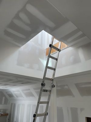A ladder is going up into a hole in the ceiling.