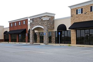 An empty parking lot in front of a row of commercial buildings
