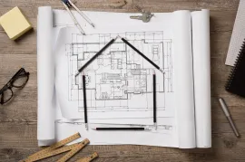A drawing of a house made out of pencils on a wooden table.