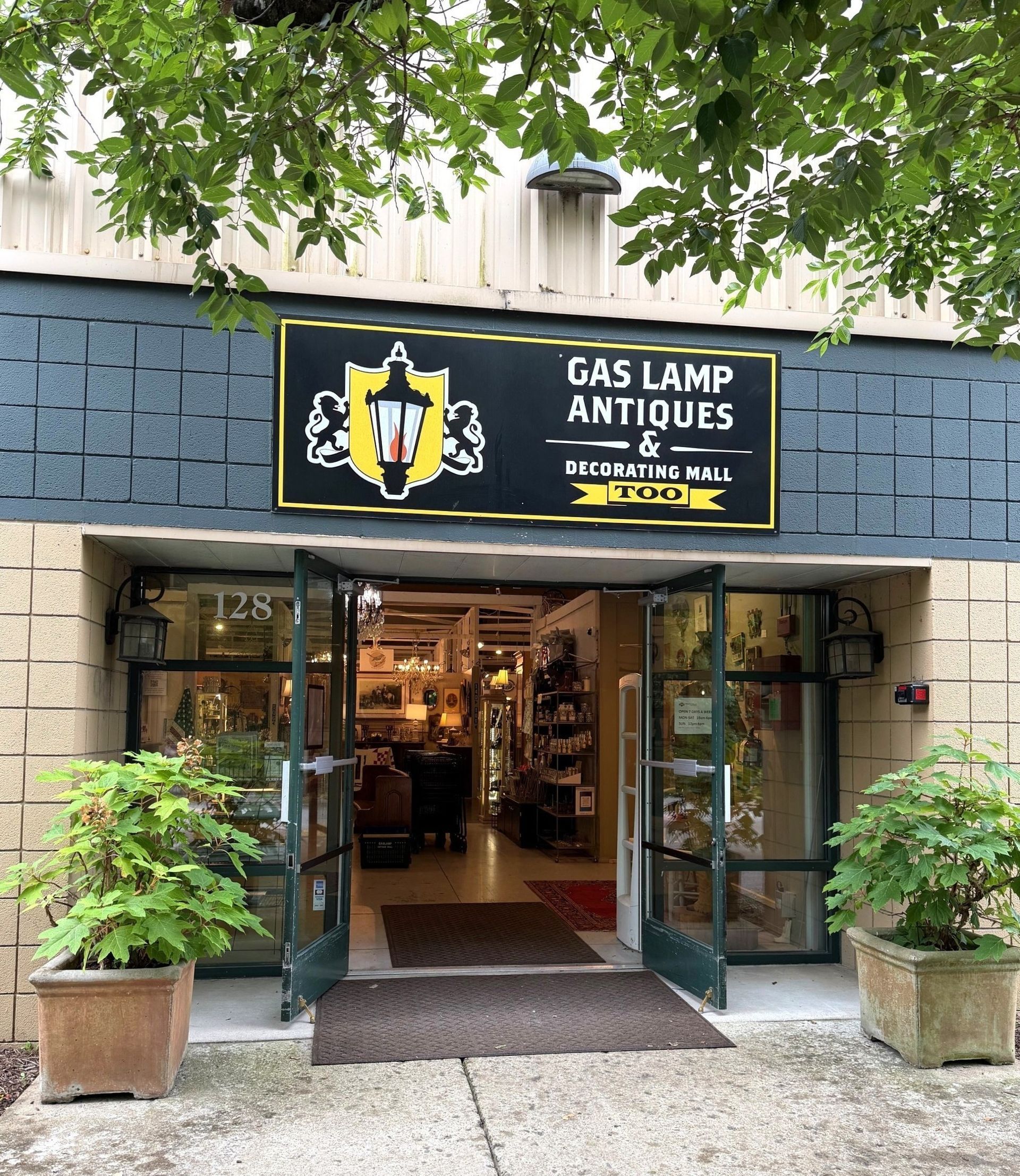 Storefront entrance for Gas Lamp Antiques with open glass doors and potted plants