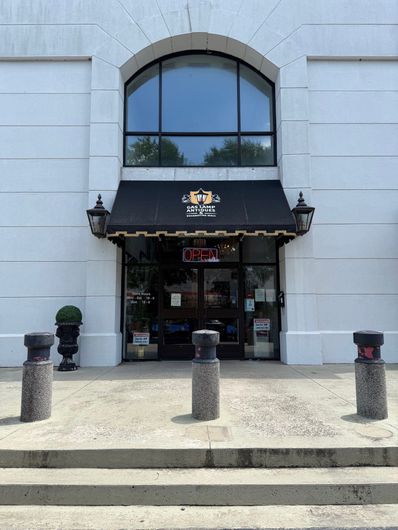 Gaslamp antique entrance with black awning, arched window, and stone bollards in front