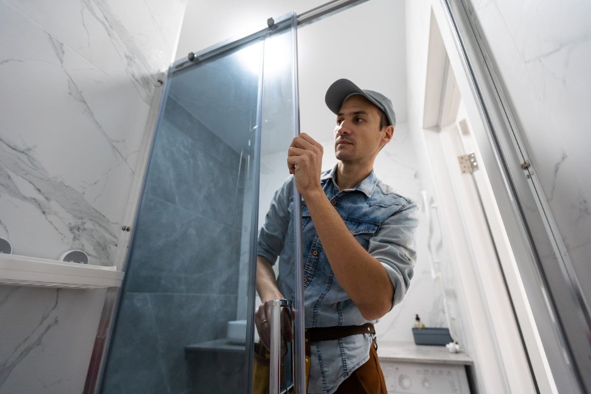 A bathroom remodeler installs a glass shower door in a Goodyear, AZ bathroom.