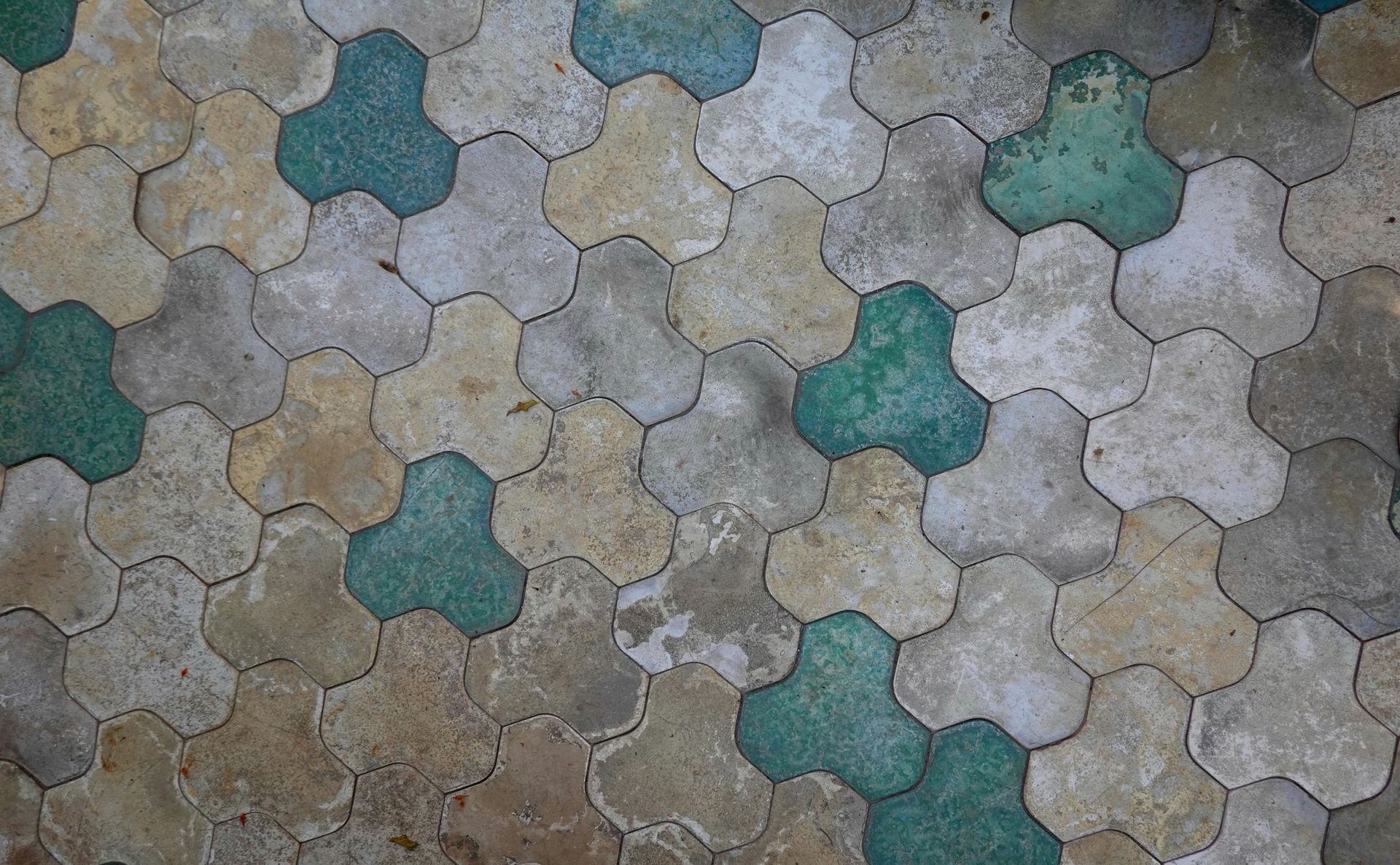 Cement floor tiles in mixed earth tones and teal accents arranged in a geometric pattern for a unique bathroom design.