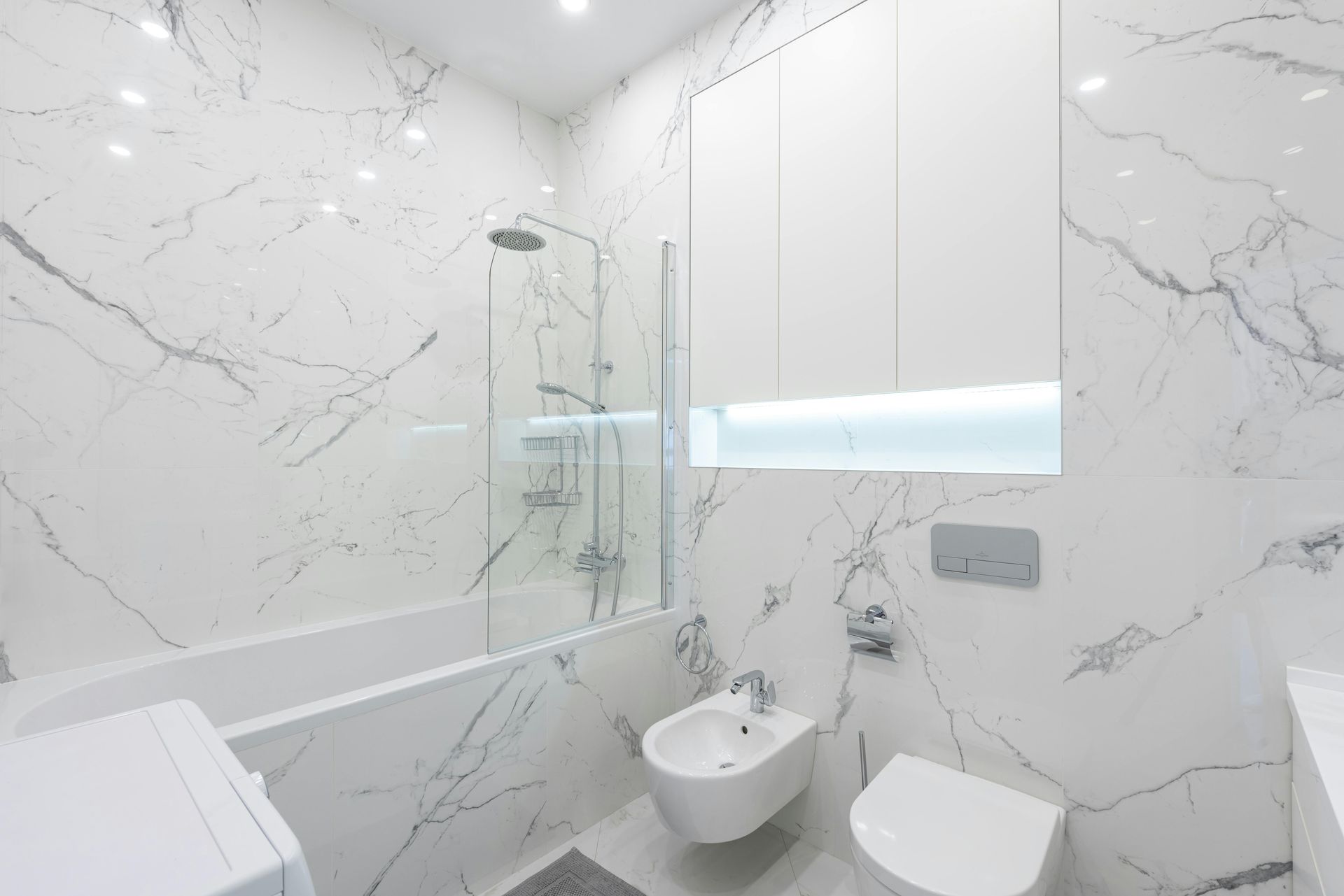 White marble-look bathroom tiles with subtle gray veining used on walls and floors for a clean, upscale design.