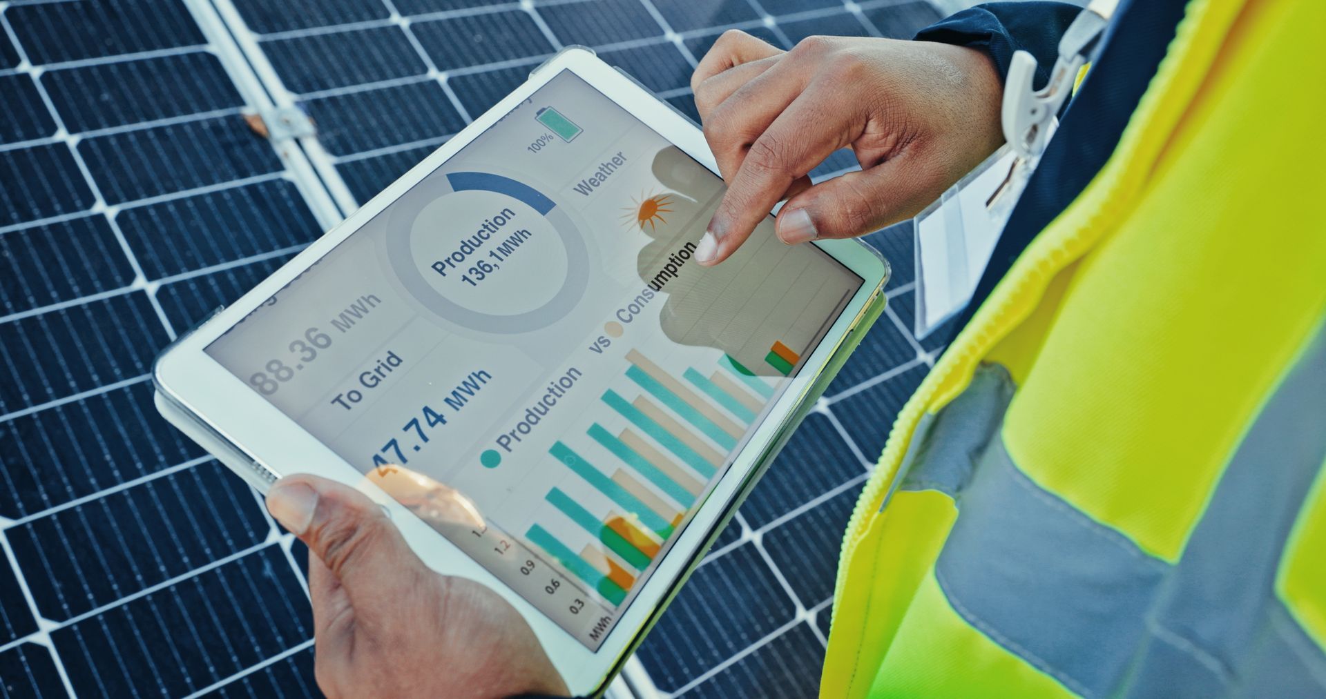 Person in a safety vest using a tablet to monitor solar panel energy production Person in a safety vest using a tablet to monitor solar panel energy production