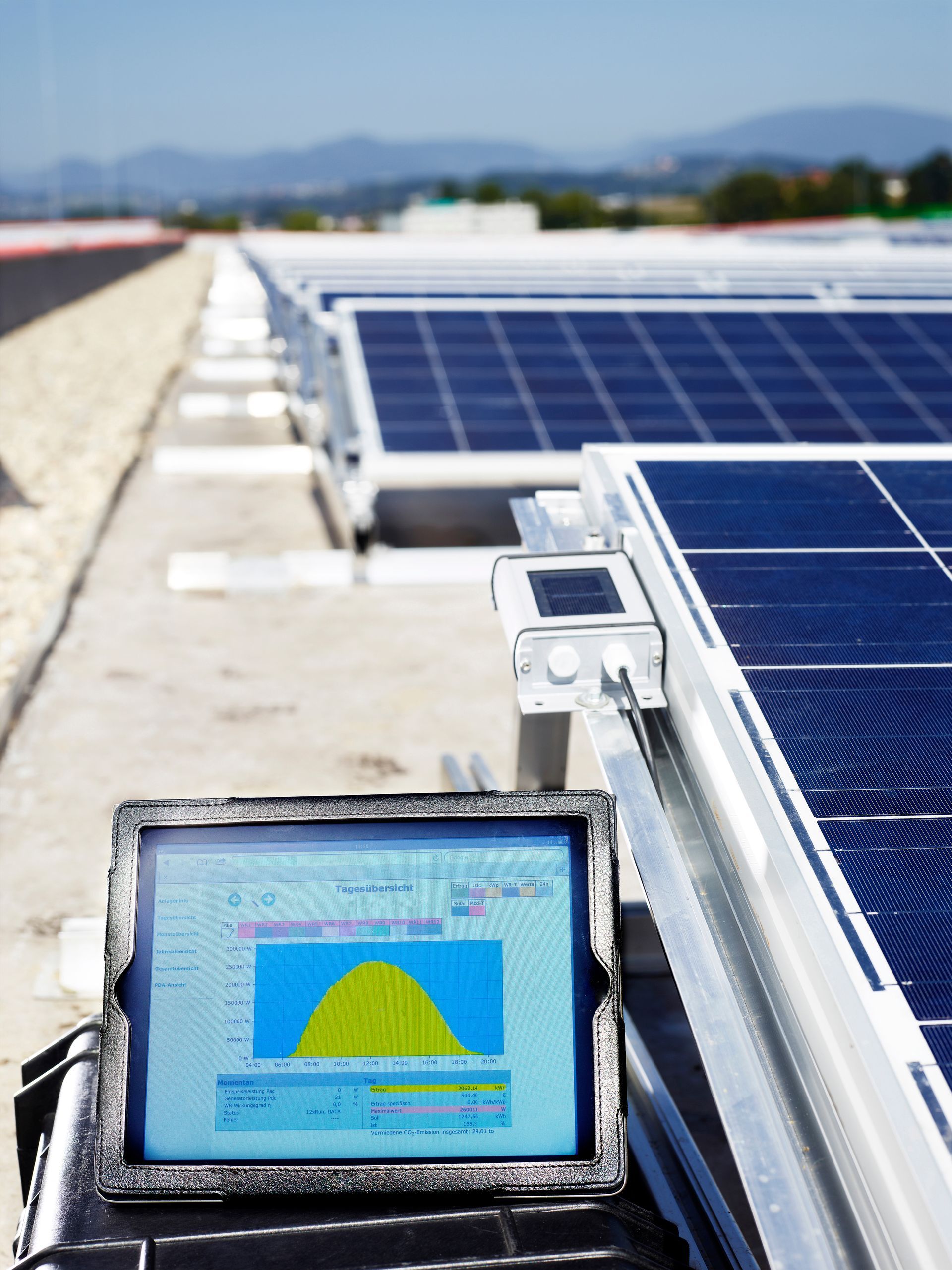 Solar panels on a rooftop, with a monitor displaying performance data Solar panels on a rooftop, with a monitor displaying performance data