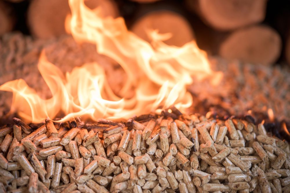 Fiamme brillanti ardono sopra un mucchio di piccoli pellet di legno cilindrici.