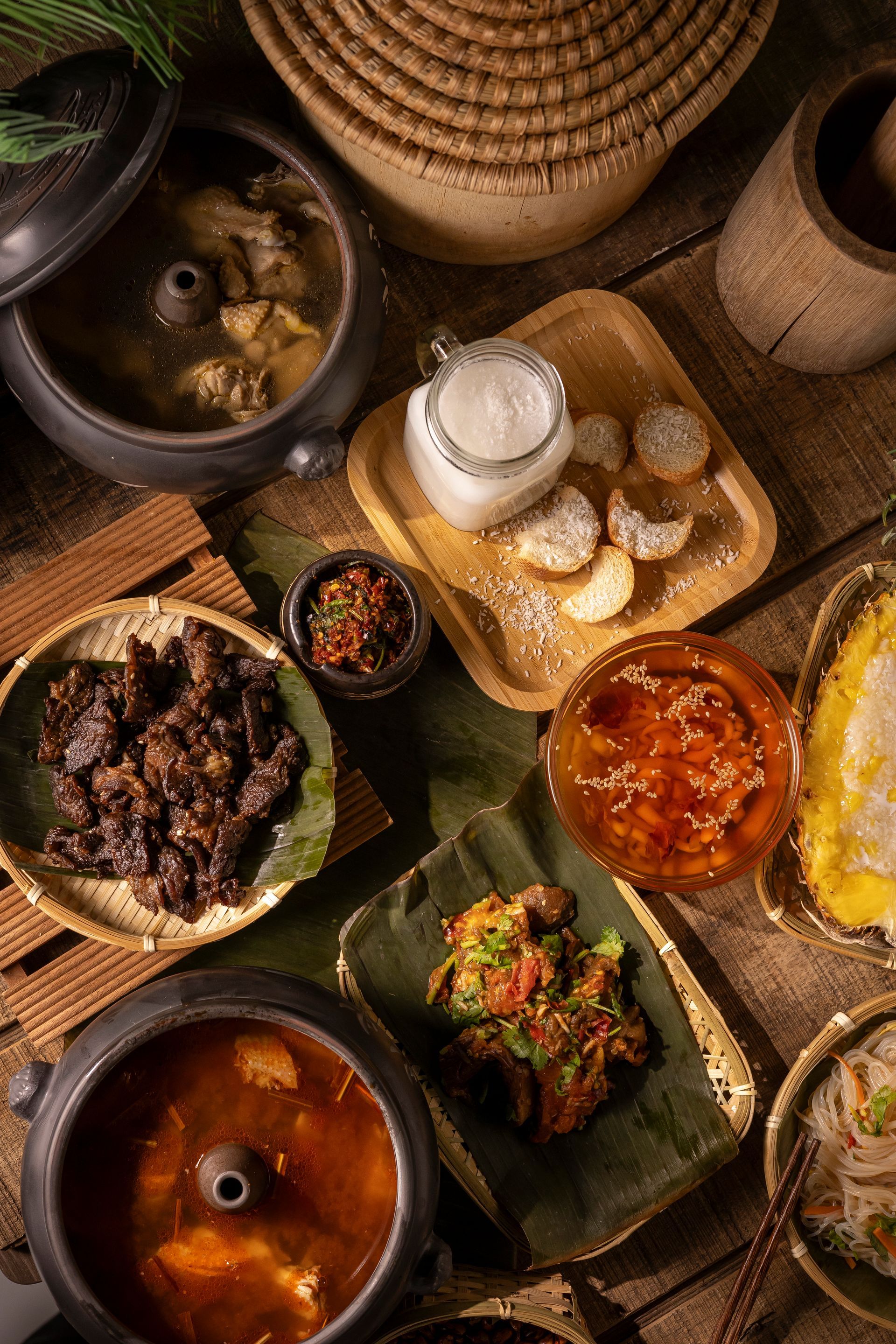 Overhead view of assorted Ethiopian dishes in clay bowls with bread and sauces on a woven mat