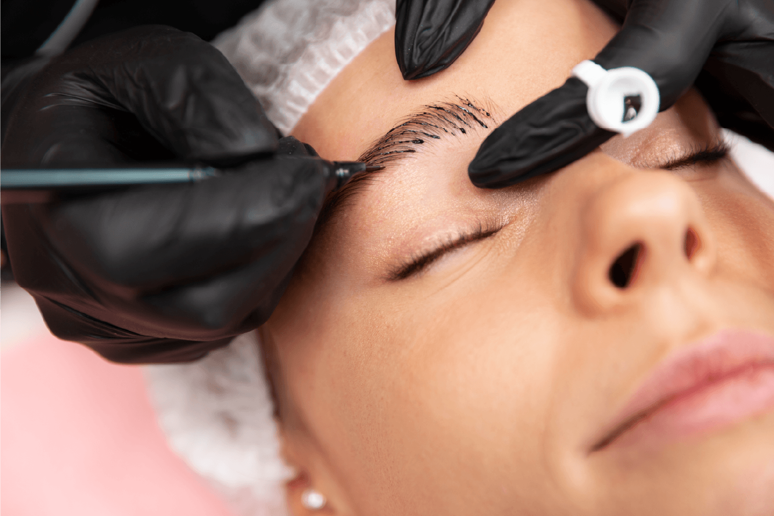 Persona que se hace microblading en las cejas, realizado con manos enguantadas, primer plano.