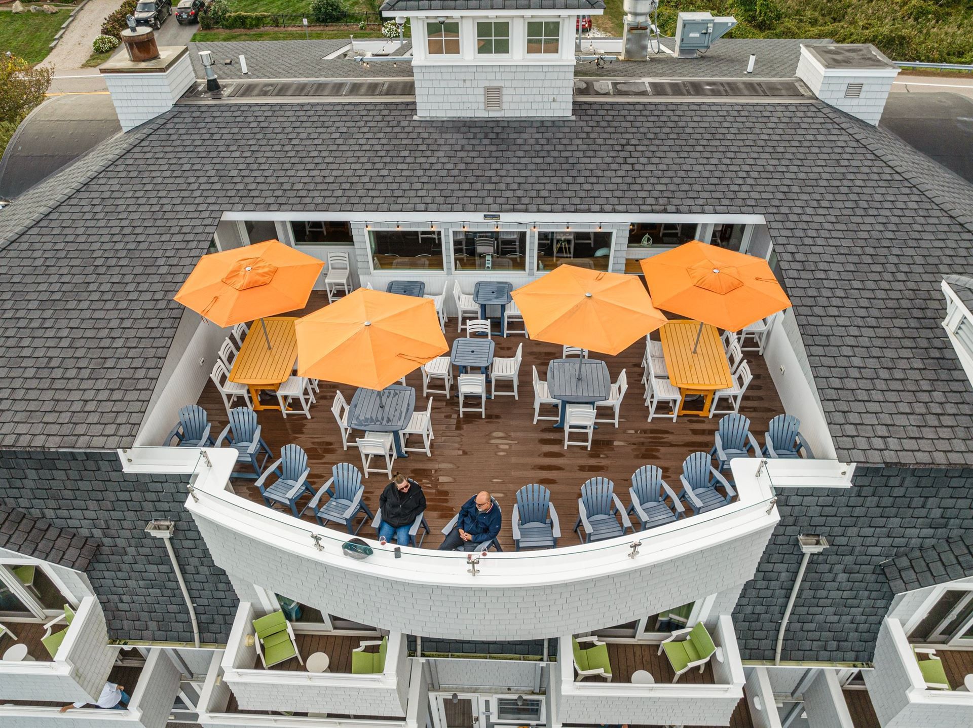 An aerial view of a rooftop deck with tables and chairs and orange umbrellas.
