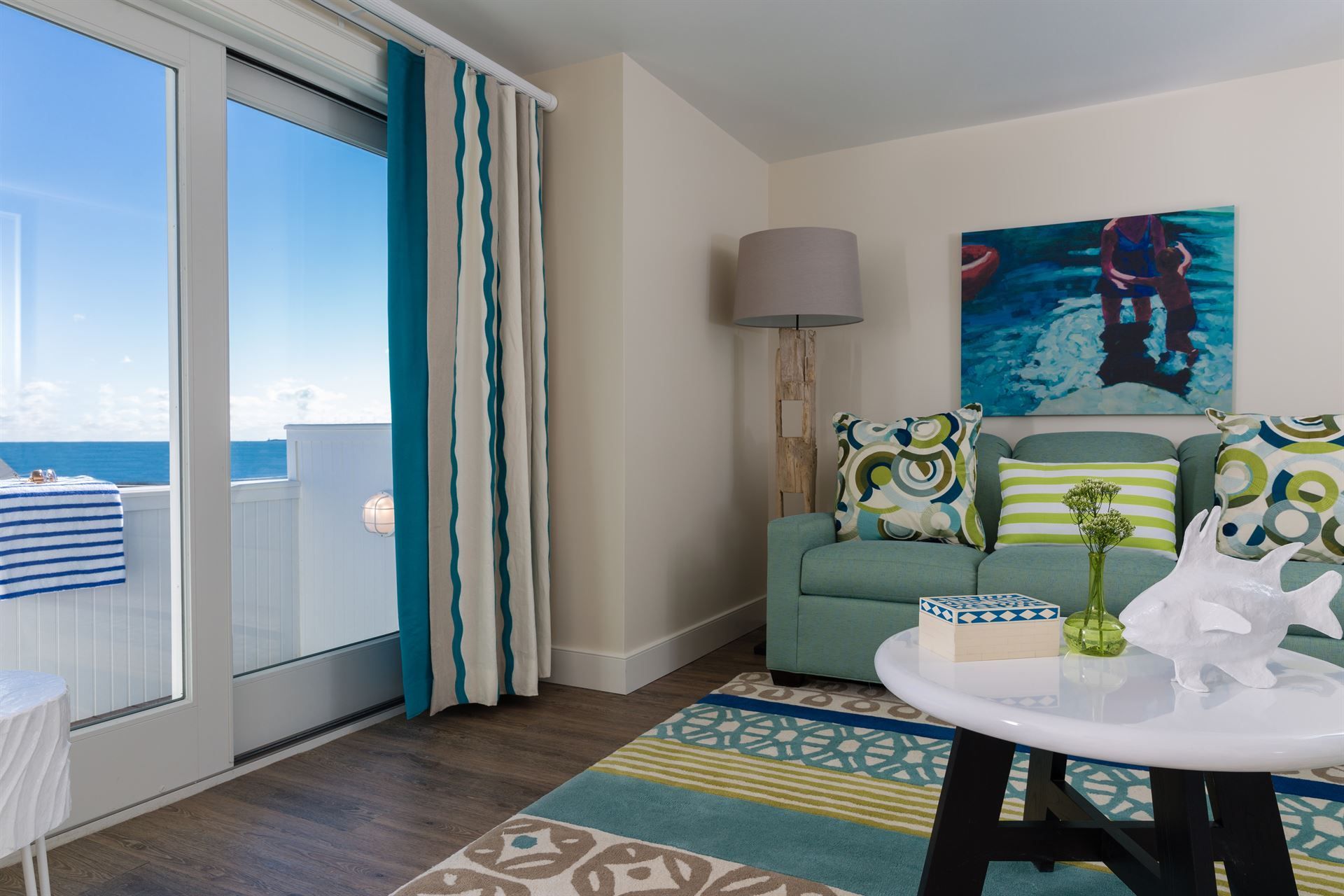 A living room with a couch and a table with a view of the ocean.