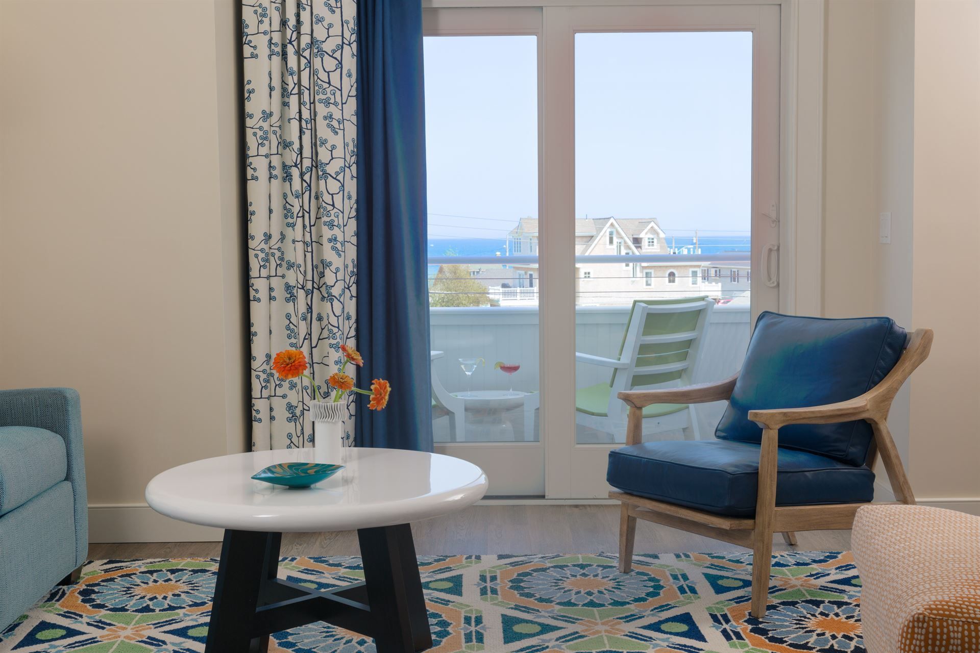 A living room with a couch , chair , table and sliding glass doors with a view of the ocean.