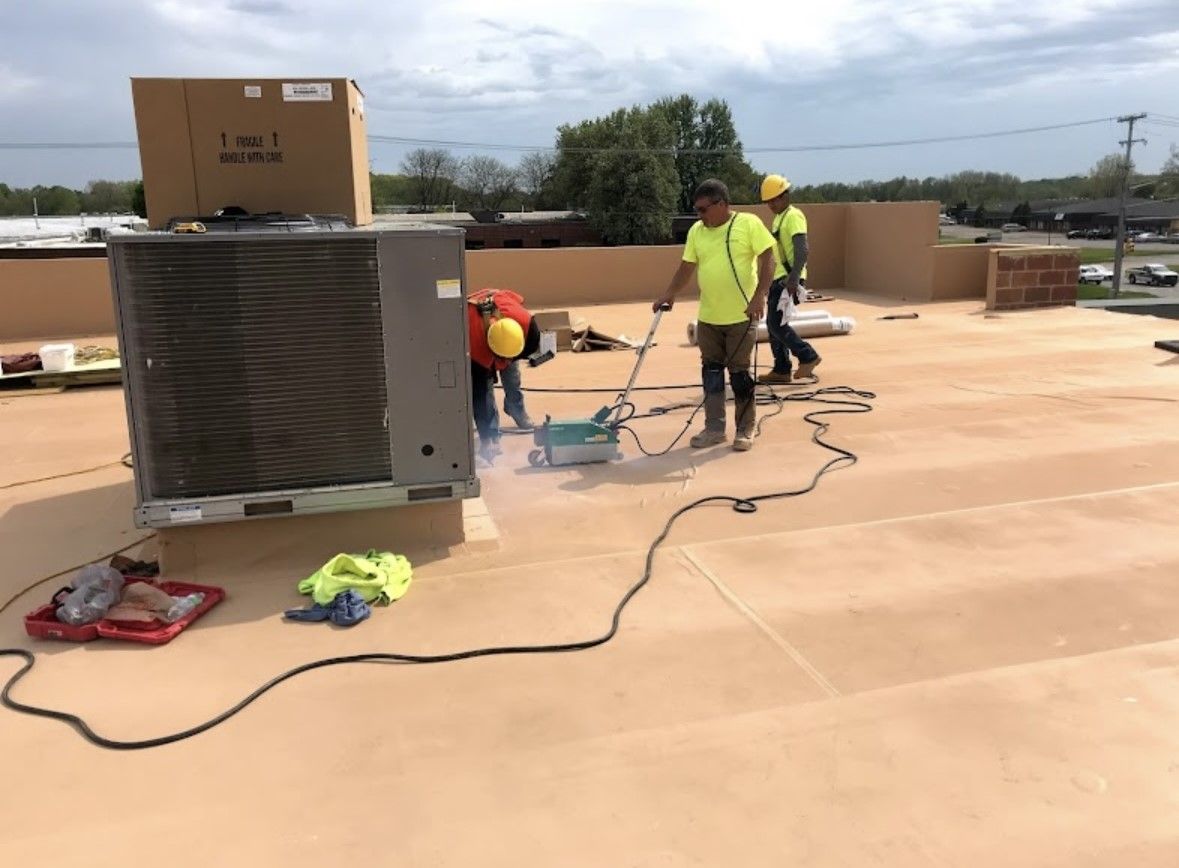 Workers repairing rooftop HVAC equipment on a flat roof with tools and cables.