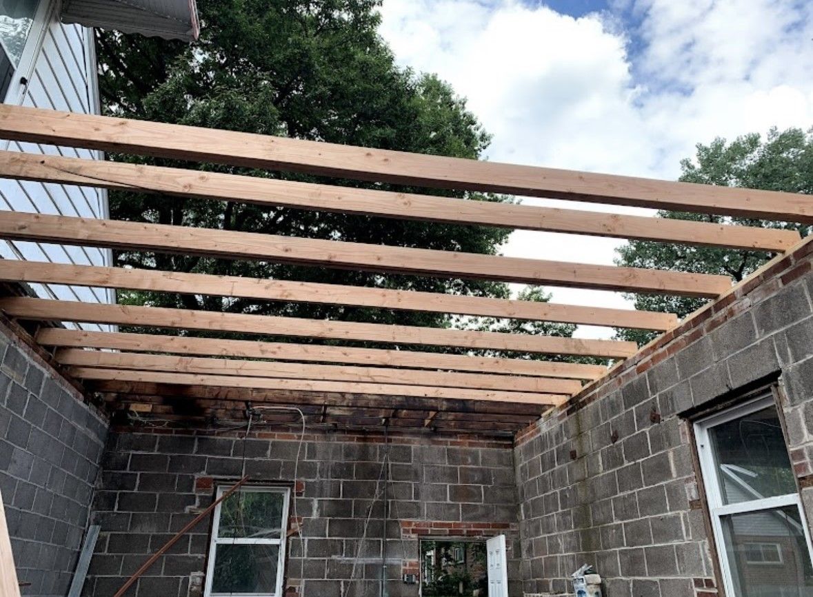 Partially built brick room with exposed wooden roof beams and open sky overhead