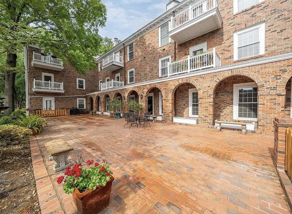 Brick apartment courtyard with arched walkways, balconies, and potted flowers on a brick patio