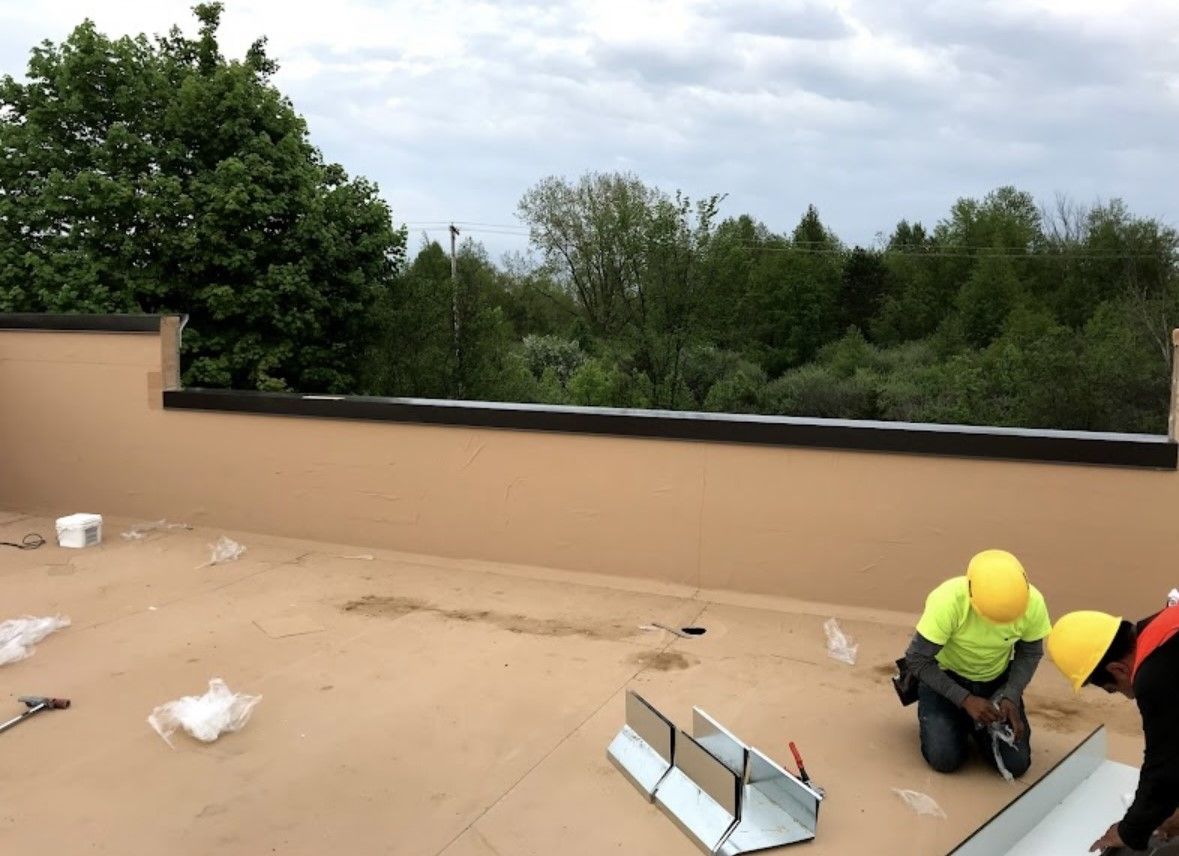 Workers in hard hats repairing a flat rooftop near the edge and vents
