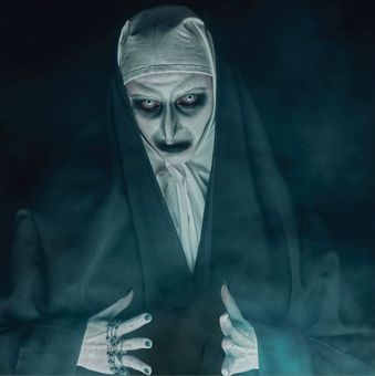 A demonic nun with pale skin, glowing eyes, and dark makeup, surrounded by mist.