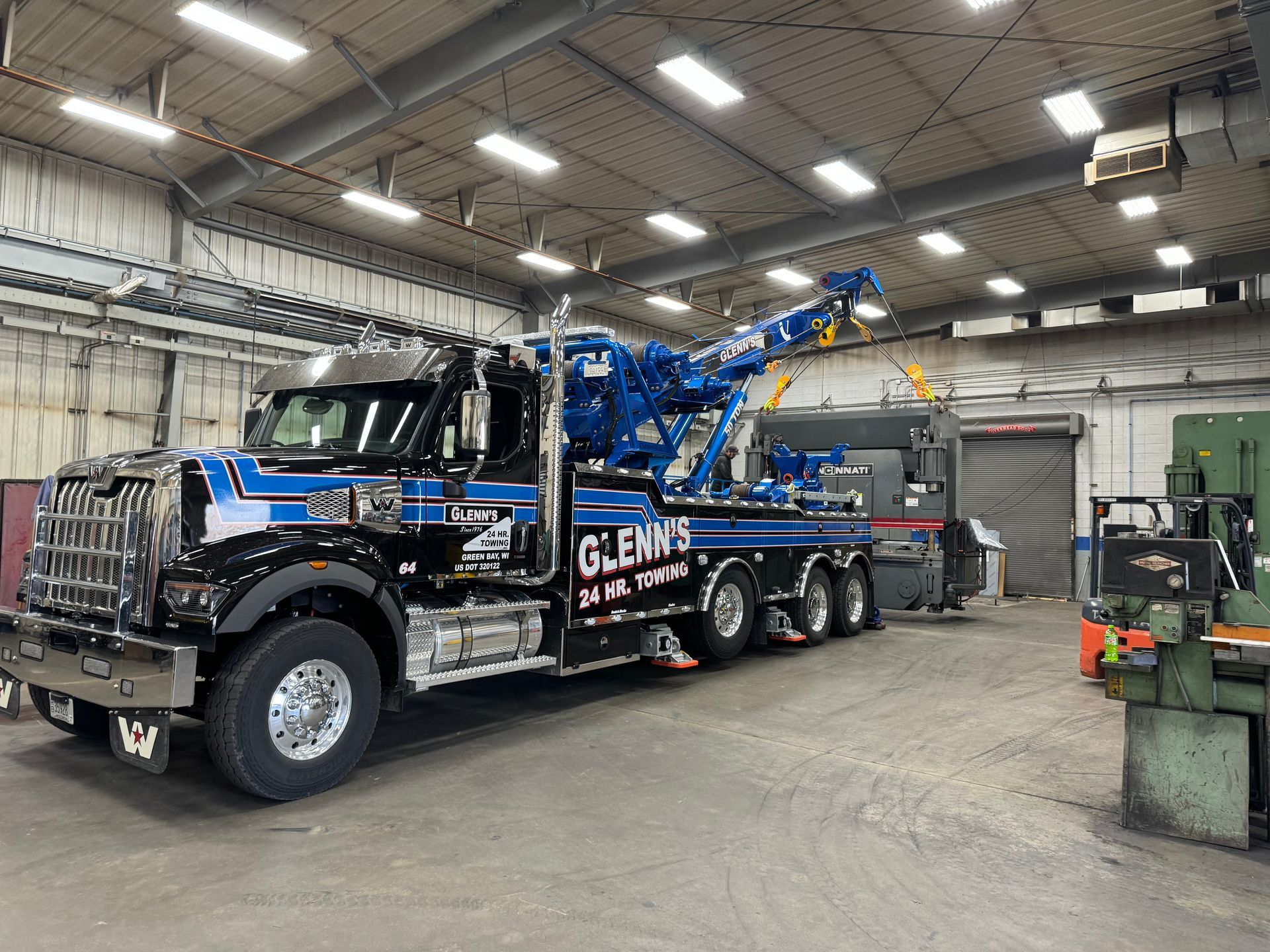 Black and blue tow truck inside a garage; 
