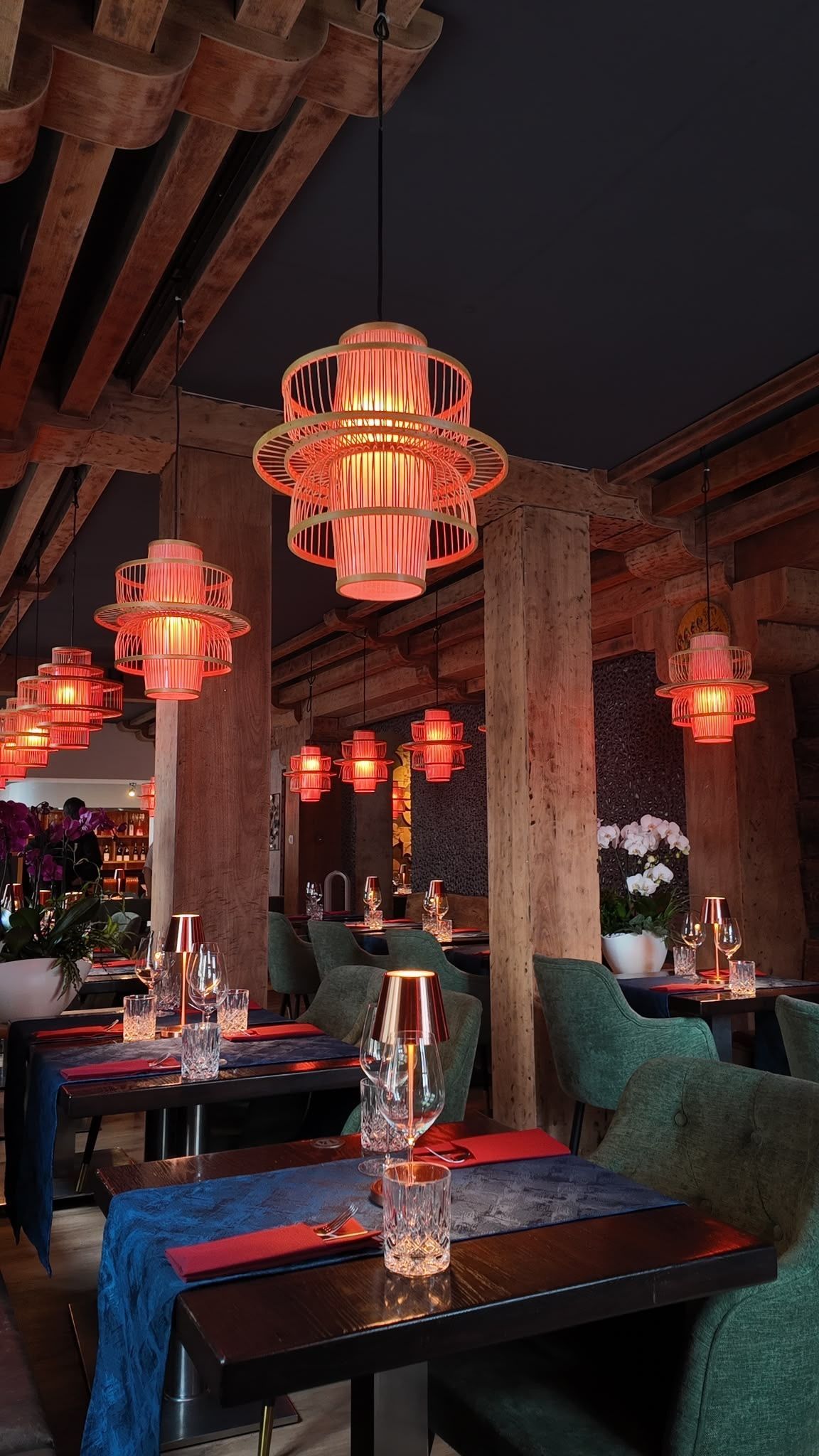 Drei farbenfrohe Cocktails auf einem weißen Tisch mit Zitrusgarnitur vor einem warmen orangefarbenen Hintergrund.