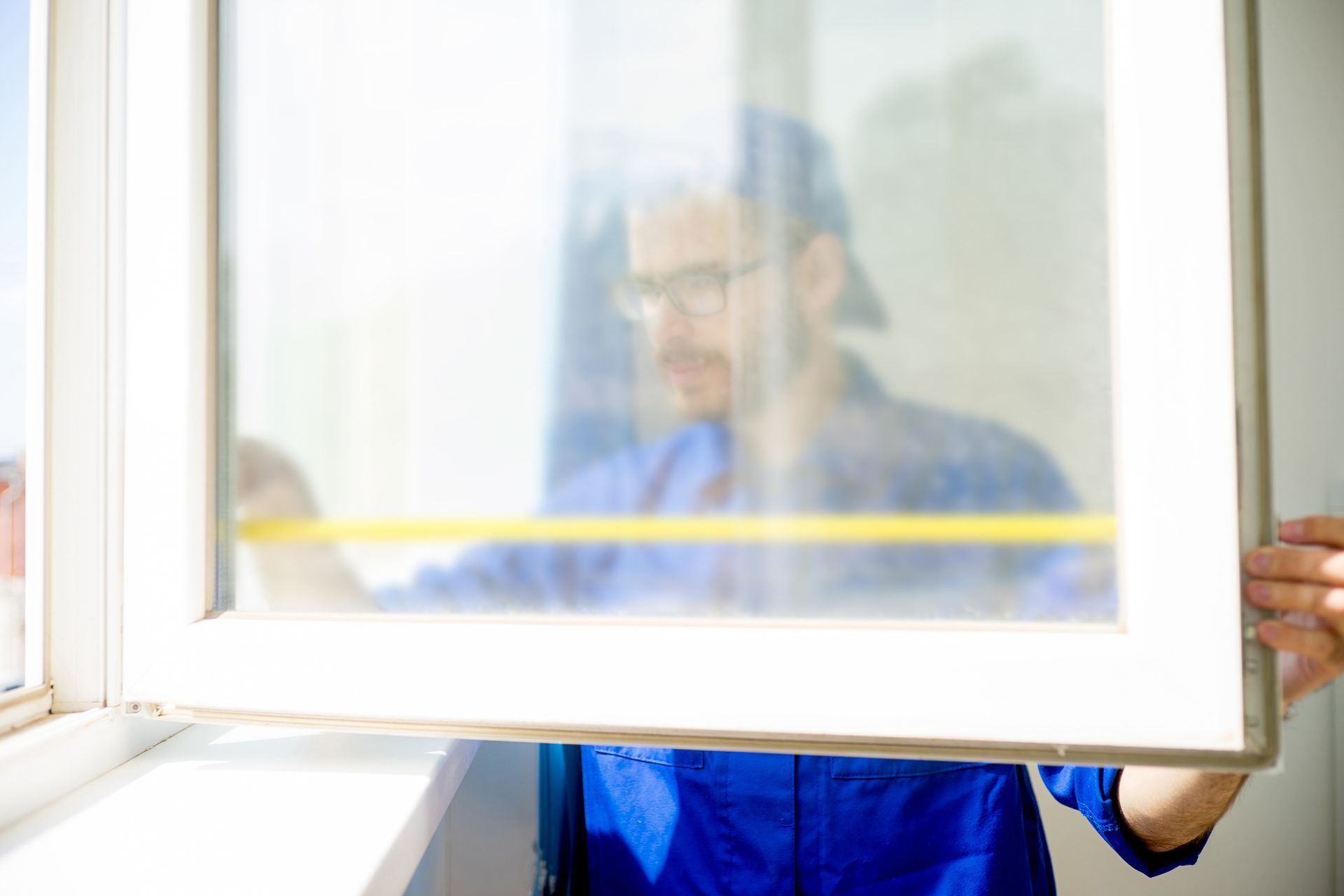 Worker measuring window frame with tape measure for home installation or repair in blue uniform. Worker measuring window frame with tape measure for home installation or repair in blue uniform.