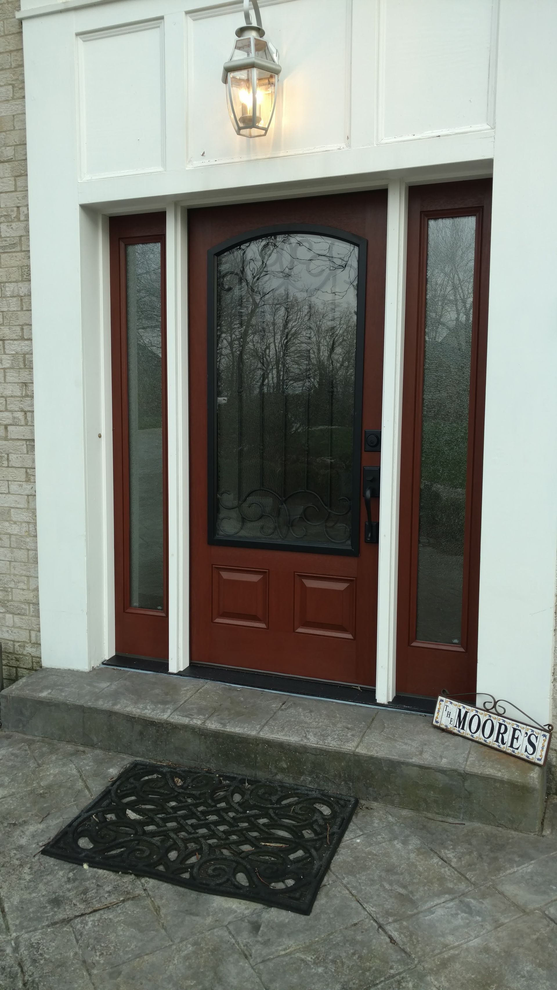 Brown front door with glass panel, sidelights, and overhead light fixture.