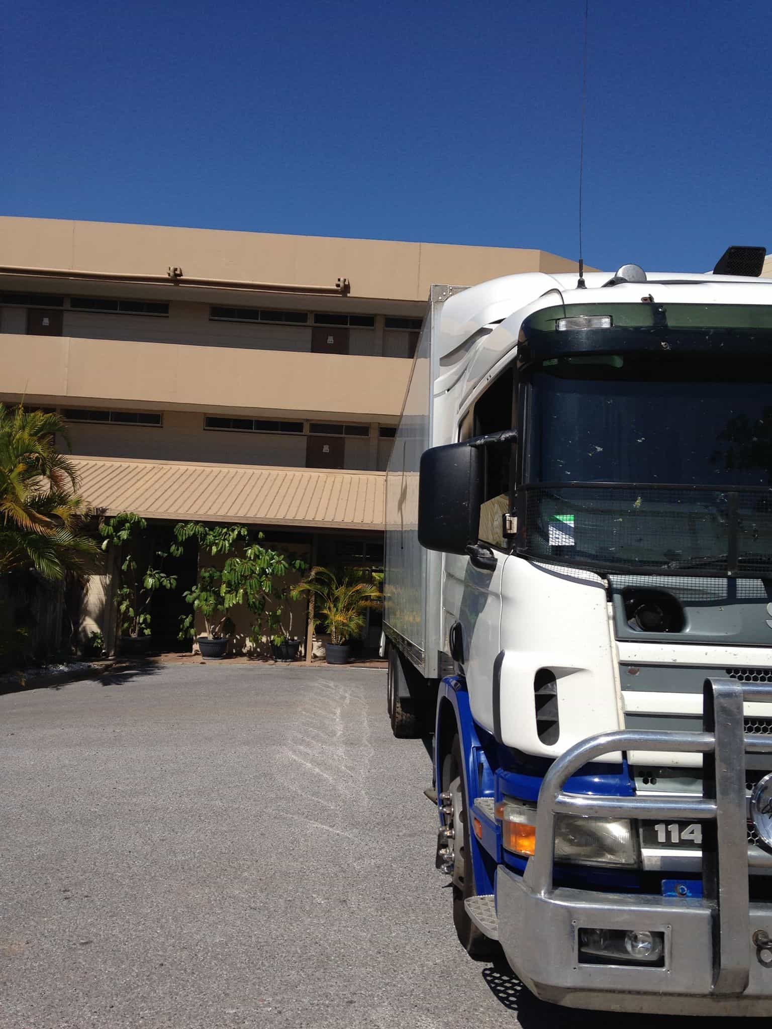 A white and blue truck is parked in front of a building — Wide Bay Removals In Dundowran, QLD
