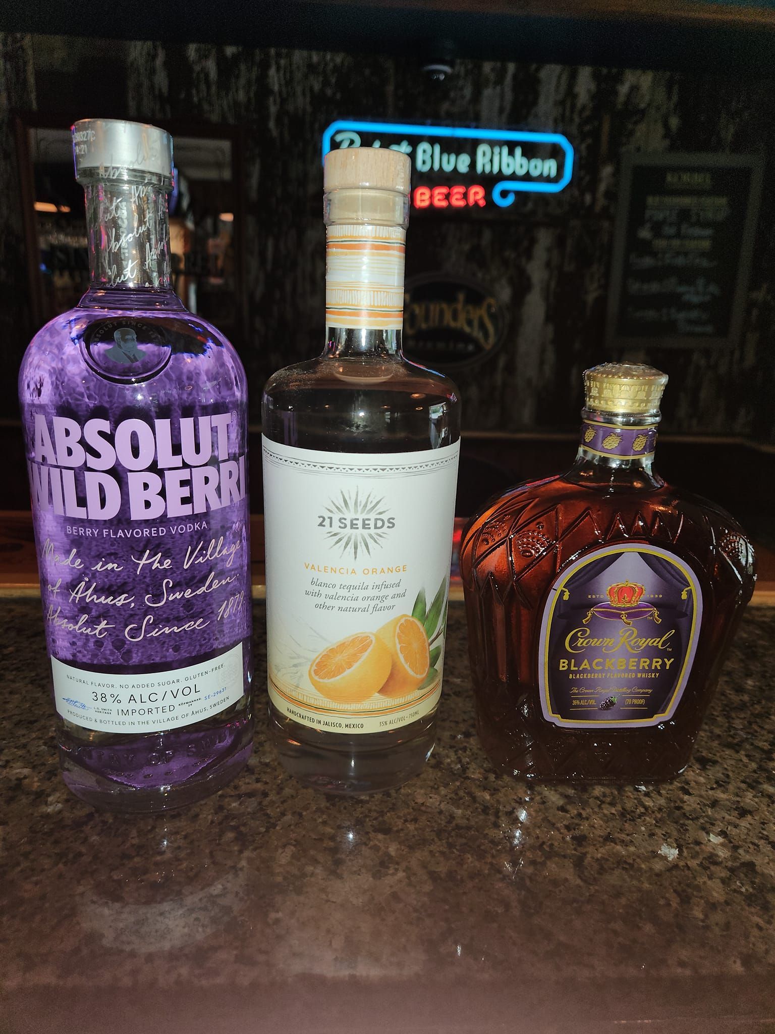 Three bottles of liquor including absolut wild berry and crown royal