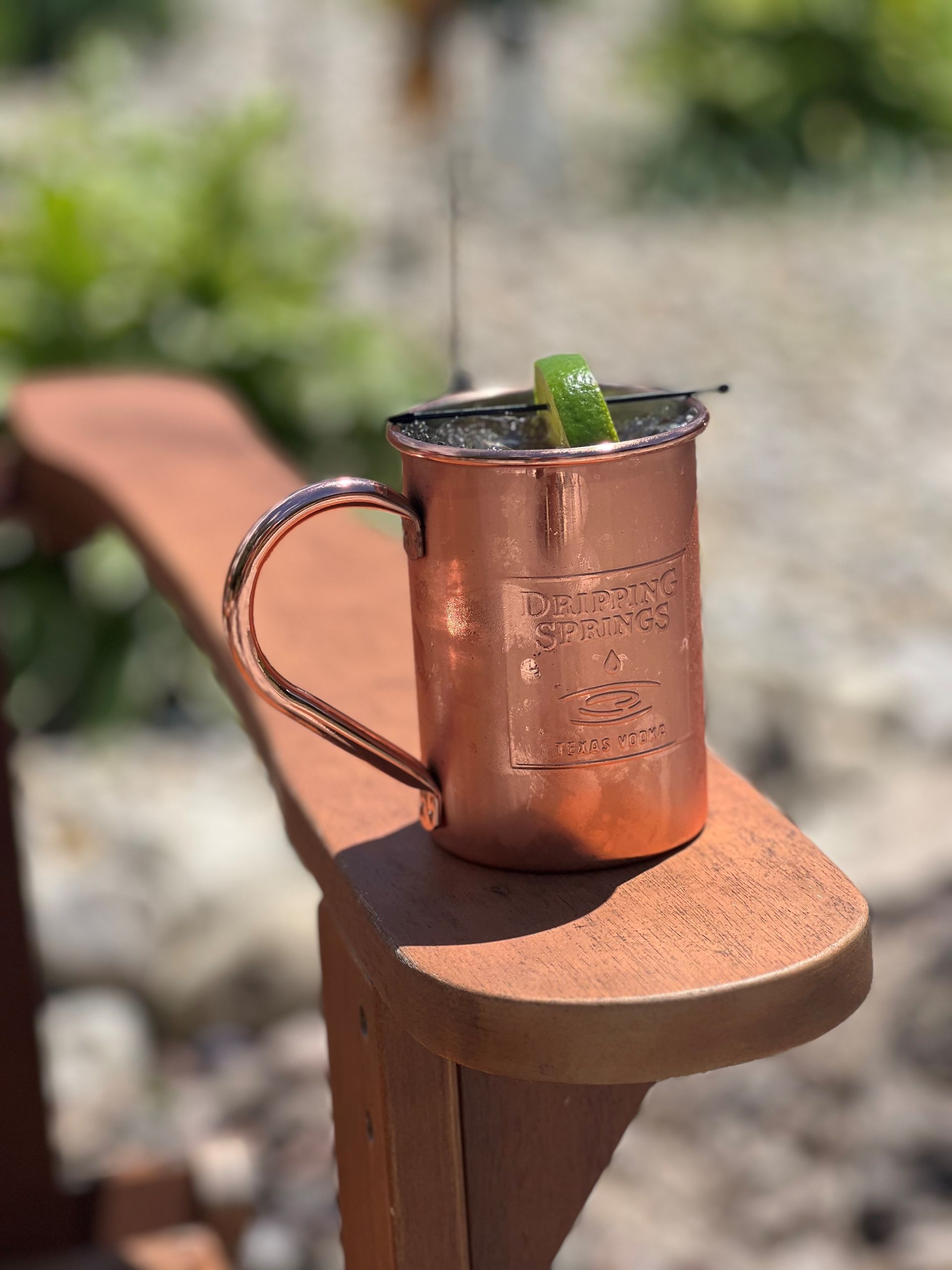 A copper mug with a drink in it is sitting on a wooden chair.