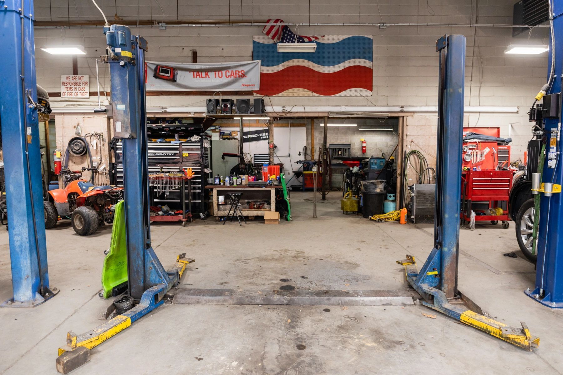 Two Blue Lifts Are in a Garage With a Flag on the Wall | Professional Auto Repair