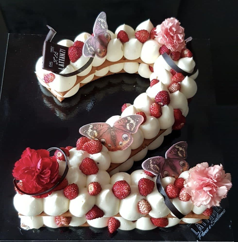 Una torta a forma di numero 2 con fragole e farfalle