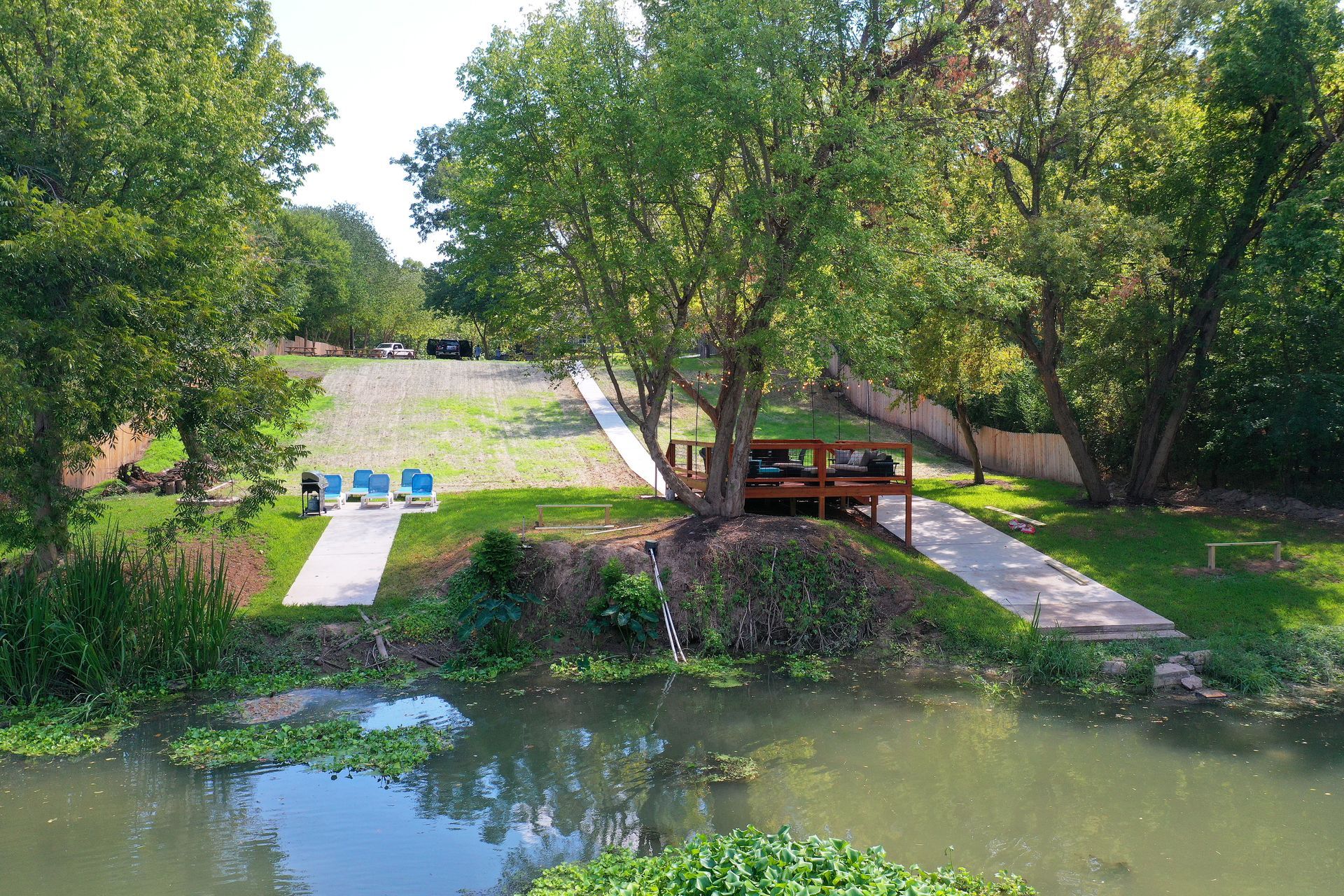 Wooden footbridge over a creek surrounded by trees and walking paths.